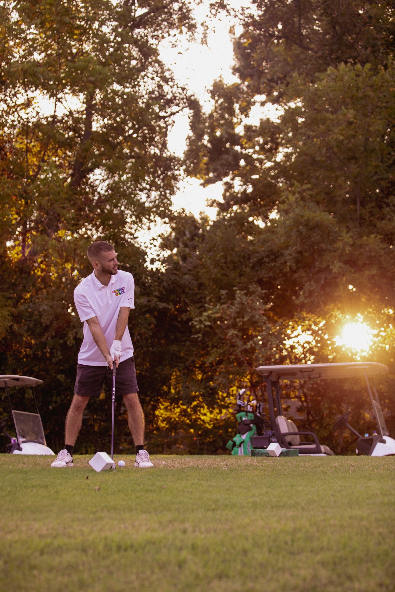 Golfer at golden hour, sun flaring through trees