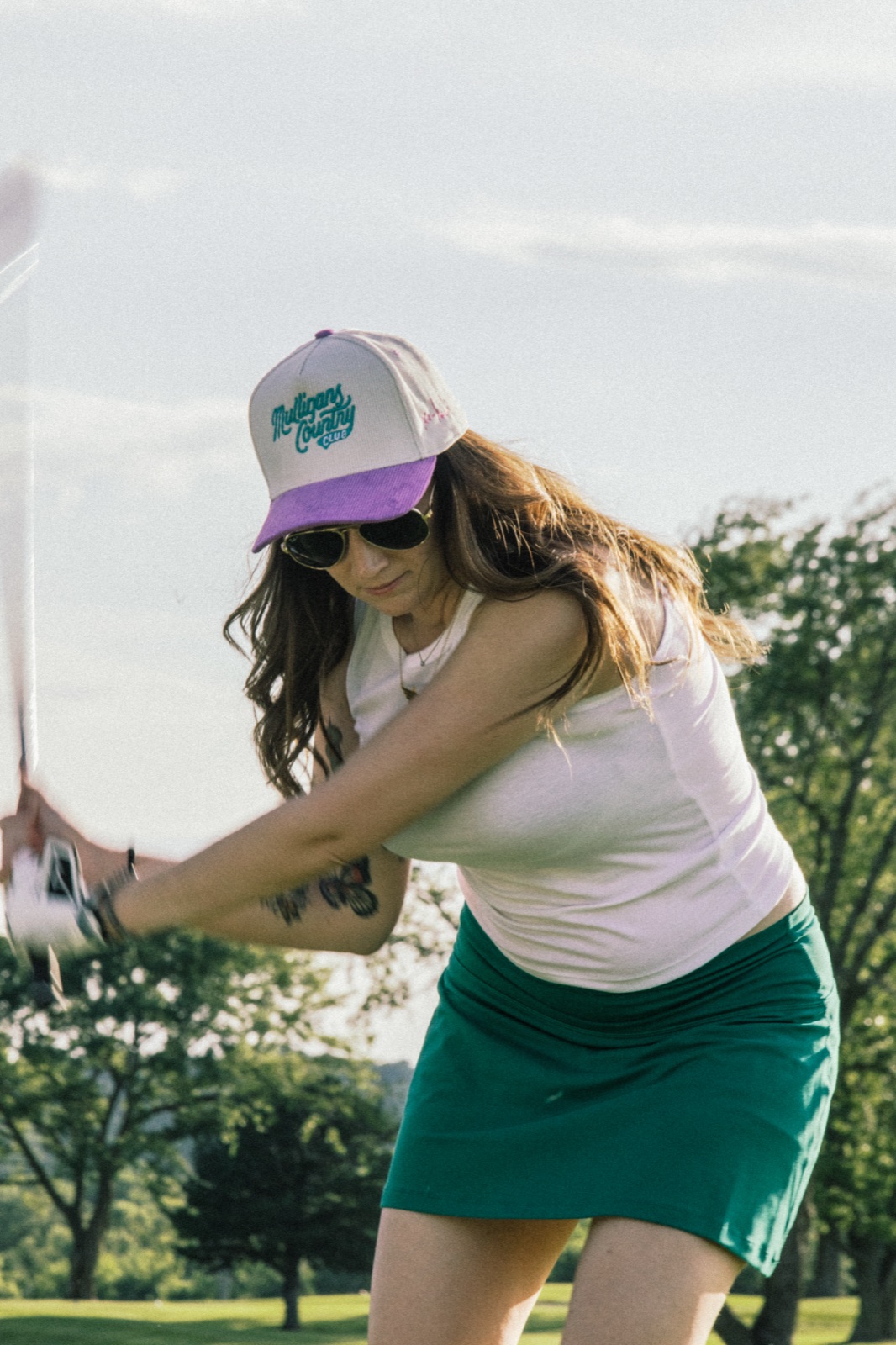 Golfer in a green skirt following through on a swing