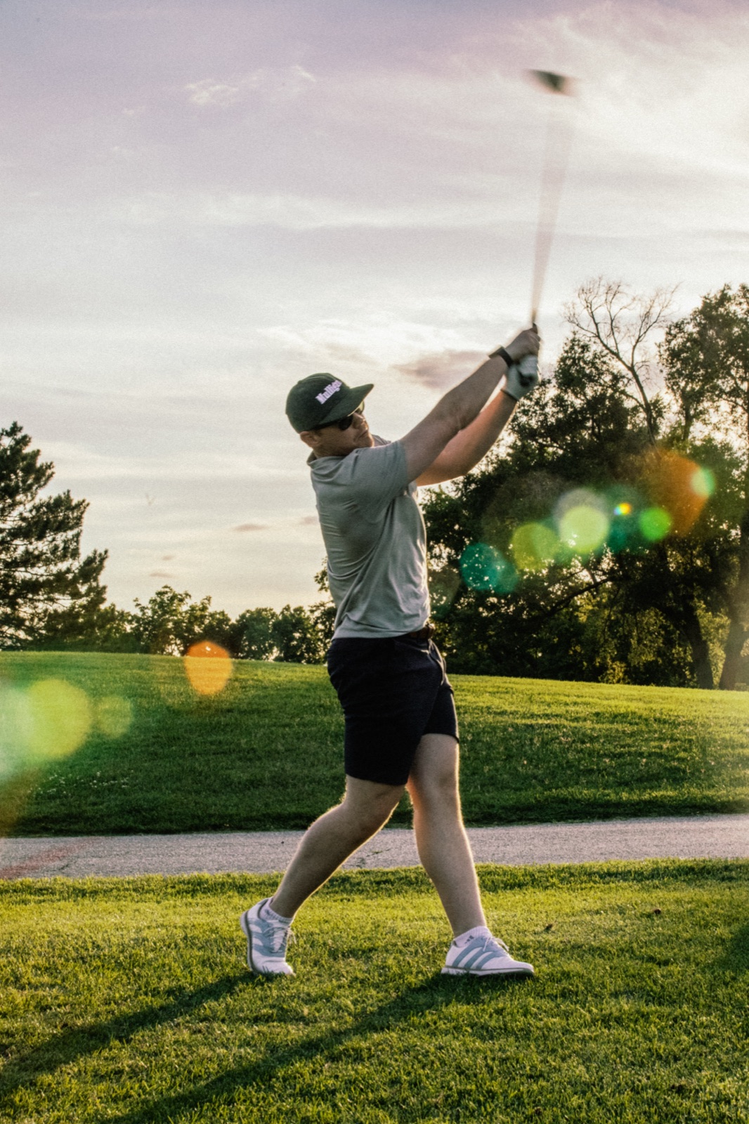 Golfer mid-swing with the sun flaring behind him