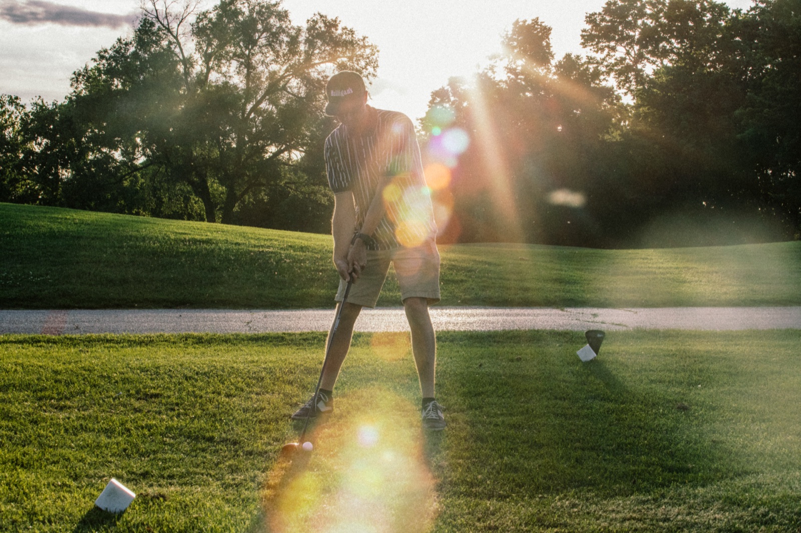 Golfer silhouetted in a full swing against the setting sun