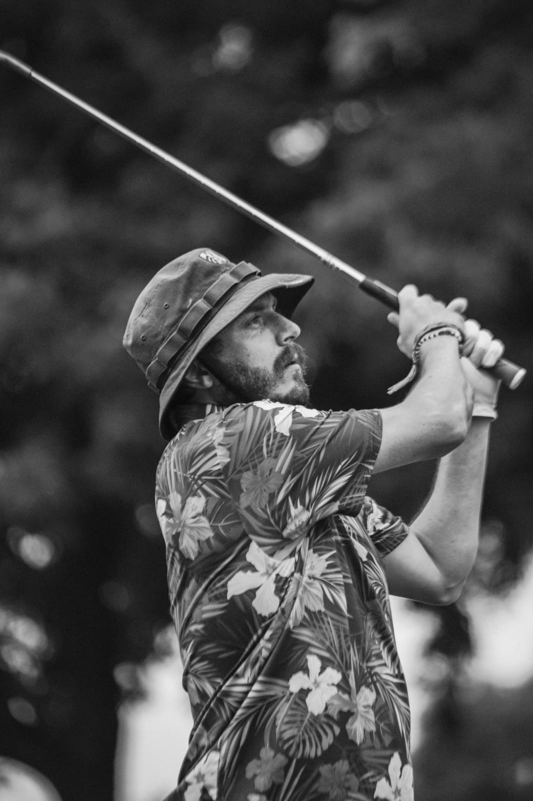 Bucket hat and floral shirt follow-through against the trees