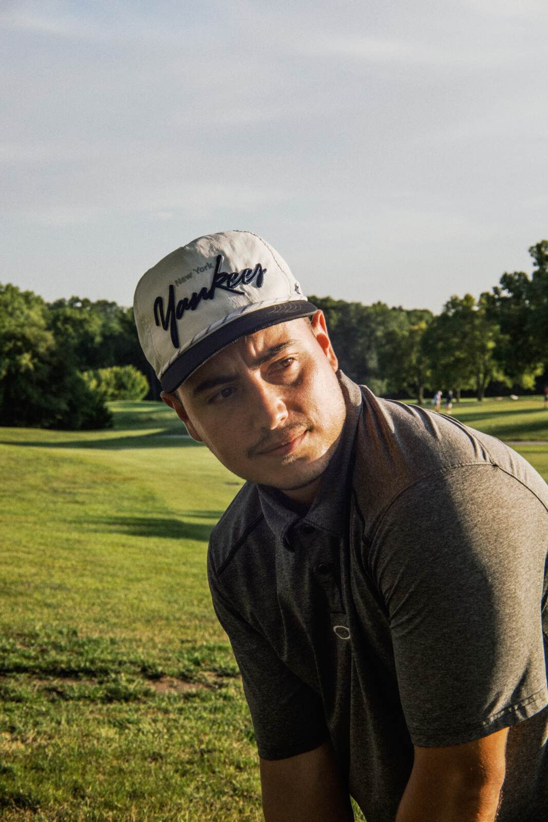 League member in a Yankees snapback squinting into the late sun