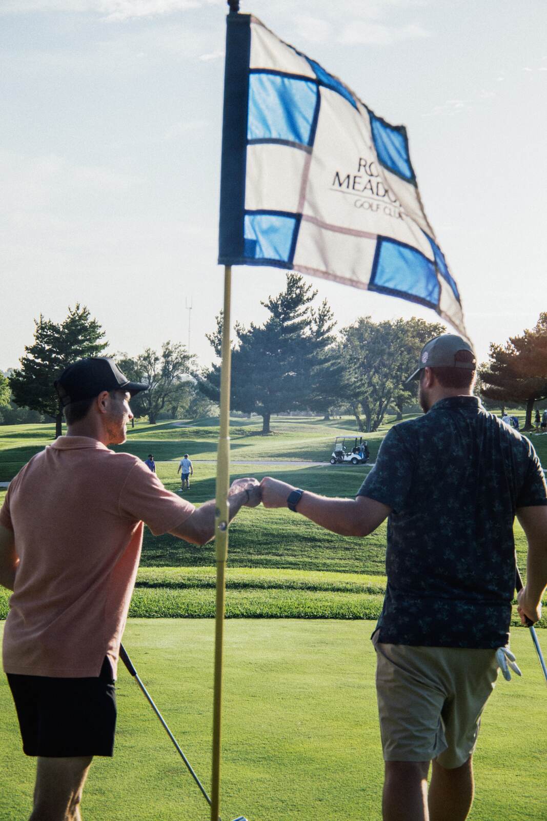 Two league members bumping fists at the flag after the hole