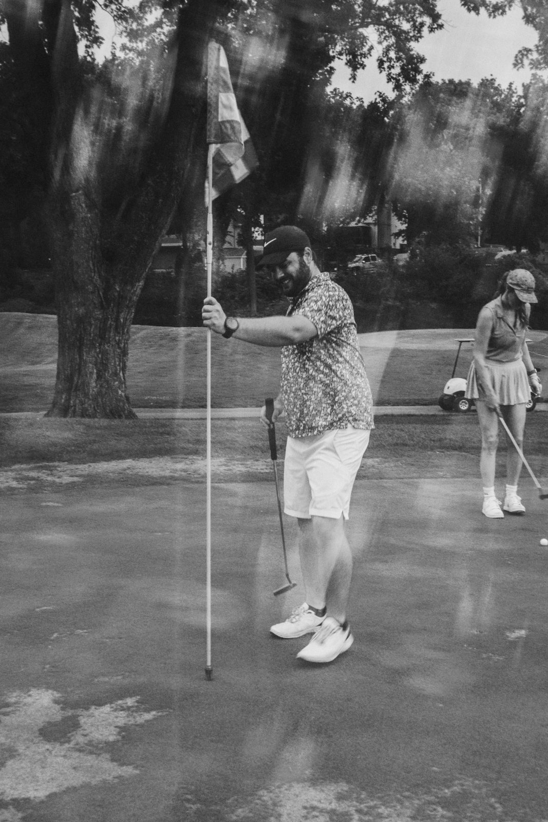 Player tending the flag at the pin while a partner reads the line