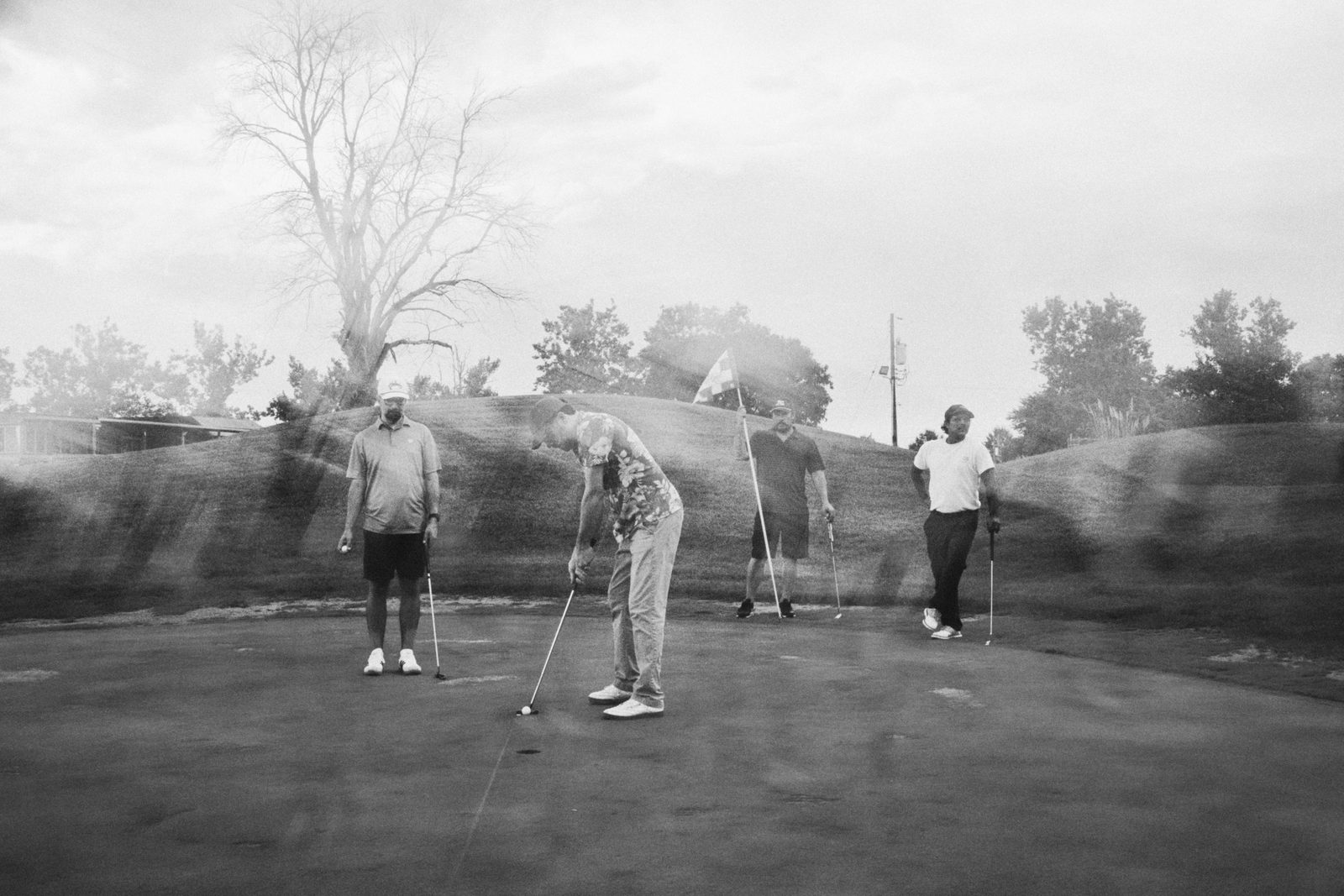 A foursome spread across the green watching a putt drop