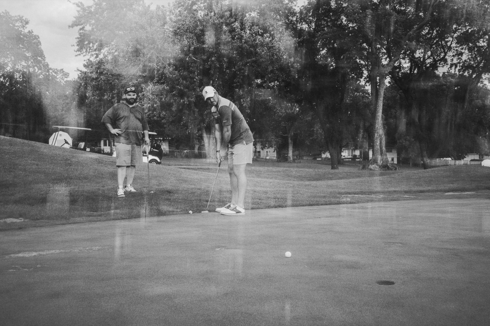 Two players reading a putt together in the last of the light